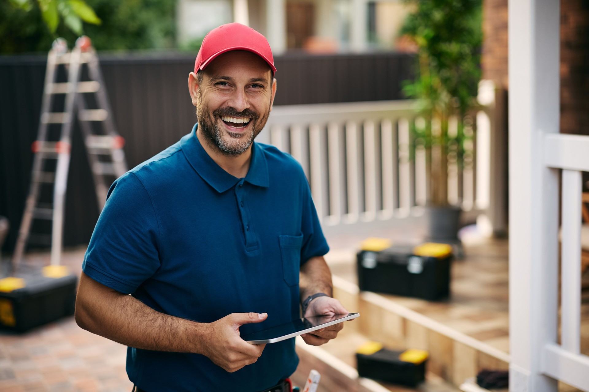 Happy handyman using touchpad during house maintenance and looking at camera.