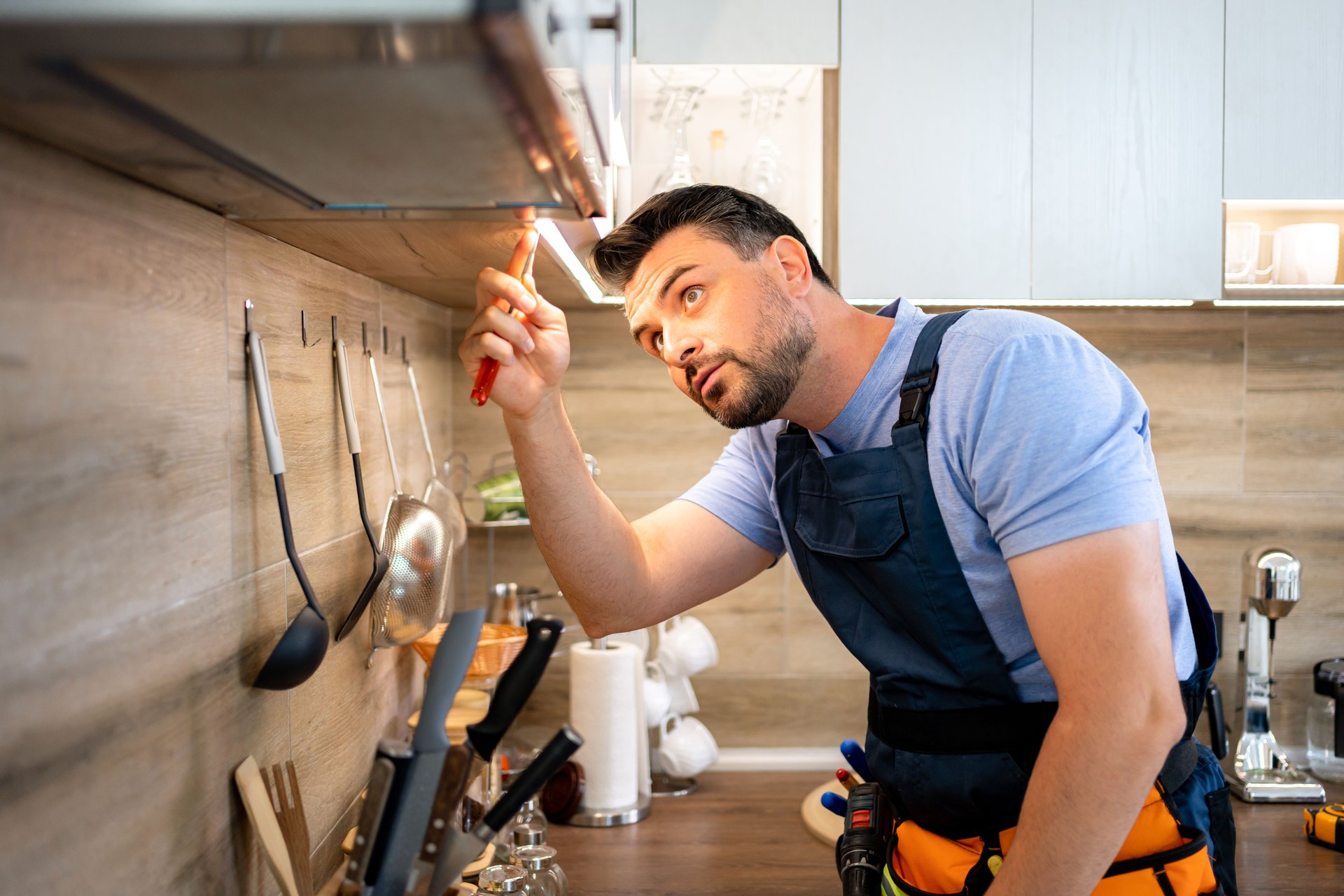 Home repair professional fixing kitchen light fixture in modern apartment